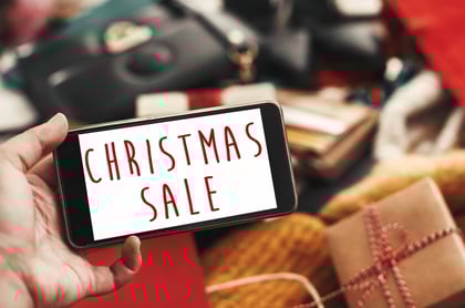 christmas-big-sale-text-phone-screen-xmas-sale-sign-special-discount-christmas-offer-sign-hand-holding-phone-with-advertising-message-credit-cards-bags-clothes-gifts