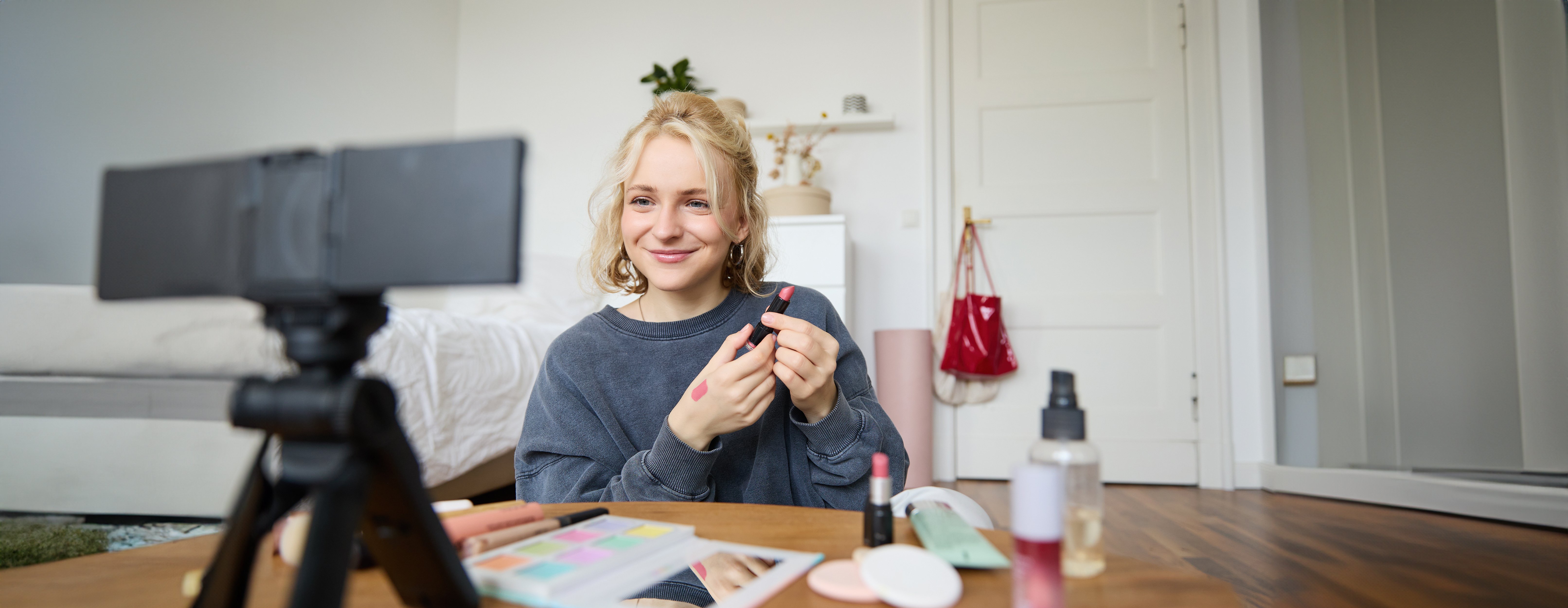 portrait-young-content-maker-woman-blogger-recording-video-digital-camera-showing-lipstick